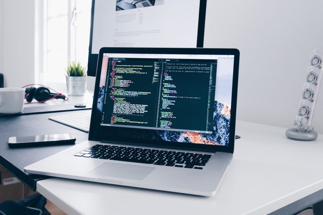 A laptop on a desk with a coding application open