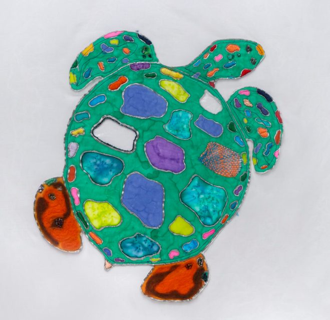 A textile rendering of a sea turtle with colorful patches
