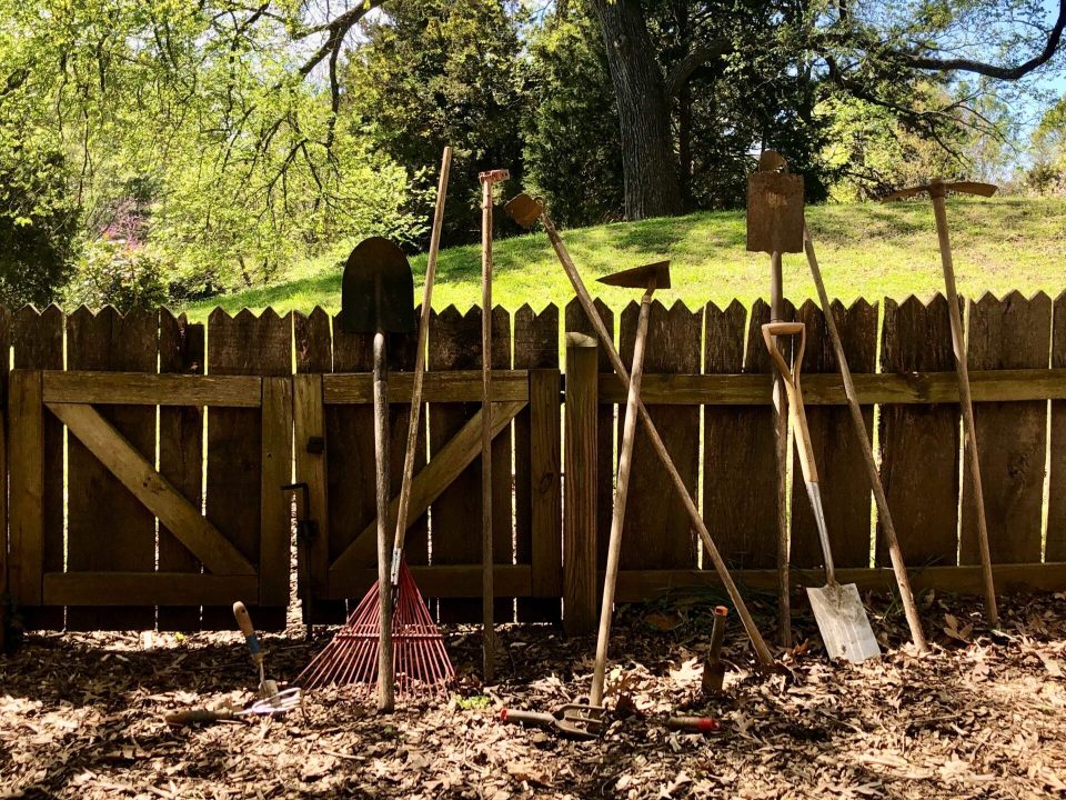 Gardening tools leaned against a wooden fence