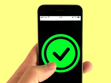 A photograph of a hand holding up a phone with a check mark on the screen