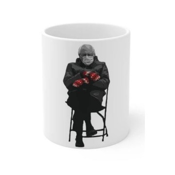 A rendering of a white mug with an image of Bernie Sanders sitting in a folding chair with his arms crossed, wearing mittens and a surgical mask