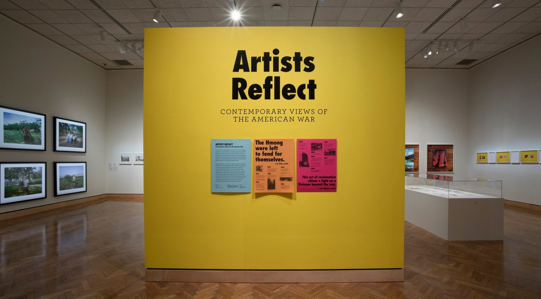 A title wall for the "Artists Reflect: Contemporary Views of the American War" exhibition, with a timeline and quotes reading "The Hmong were left to fend for themselves" and "This act of reclamation shines a light on a Vietnam beyond the war."