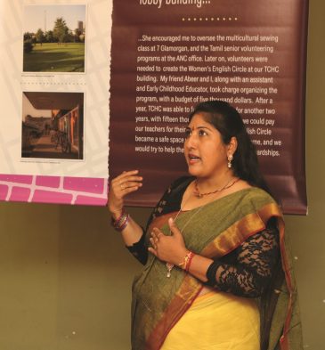 A woman stands in front of an exhibition panel explaining what's happening in the exhibition.