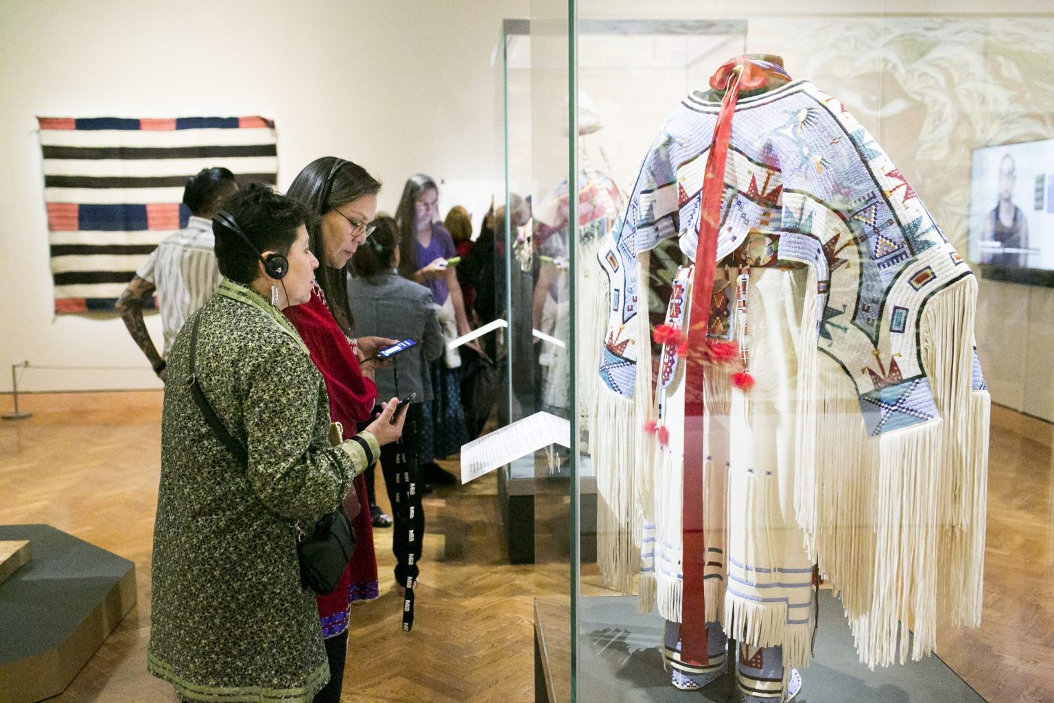 Visitors look at clothing, textiles, and video interviews displayed in galleries