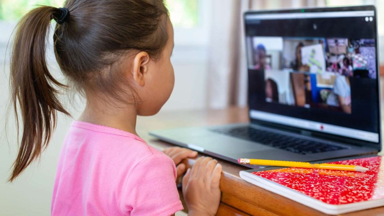 A child watching a video meeting on a laptop screen