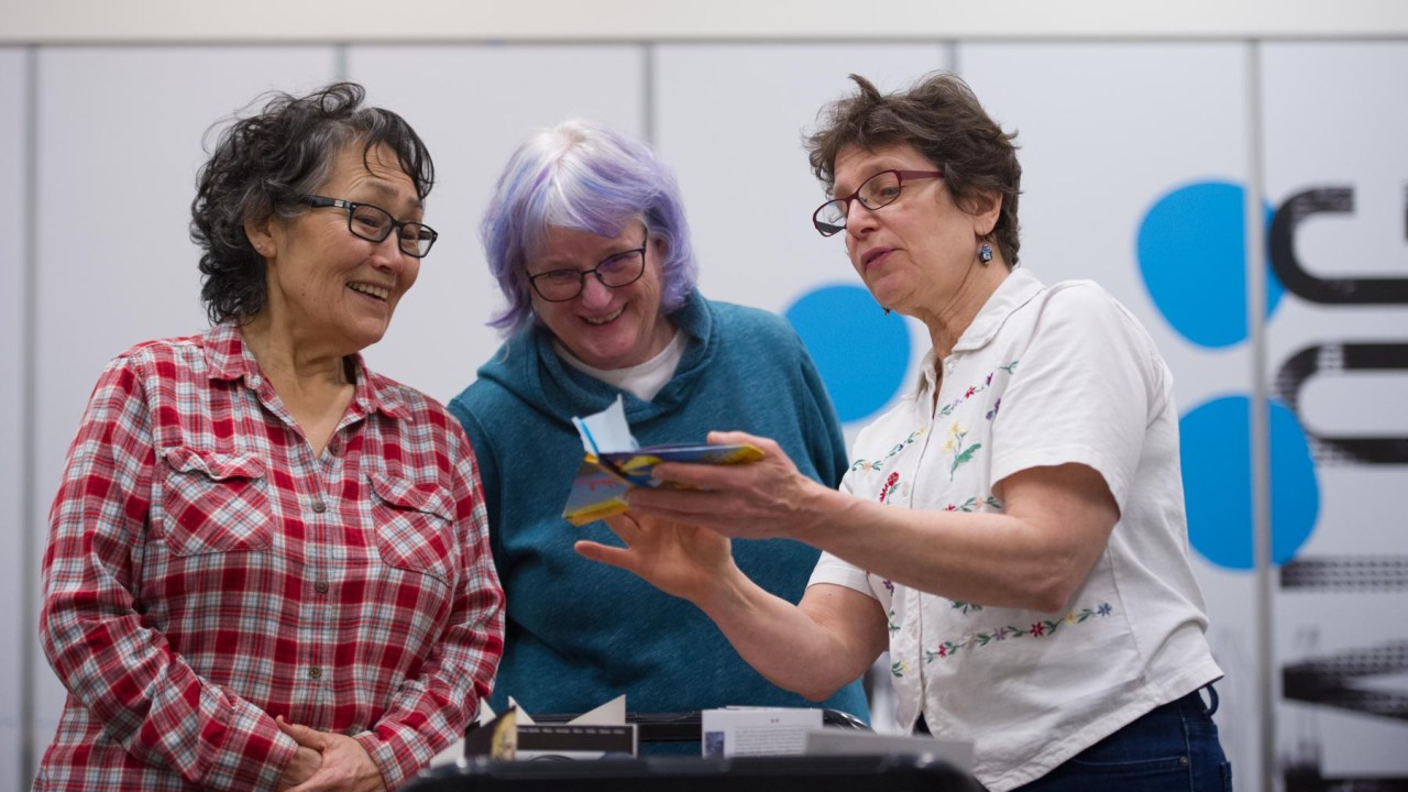 A group of people looking at an art project and smiling