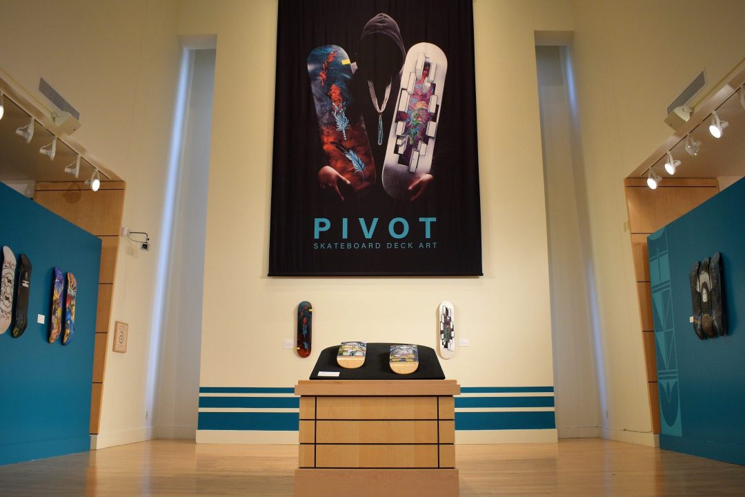 An exhibition gallery with skateboard decks and the title "PIVOT"