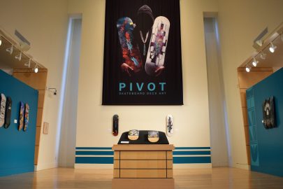 An exhibition gallery with skateboard decks and the title "PIVOT"
