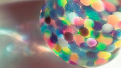 An abstract photograph of colorful sequins in a glass container