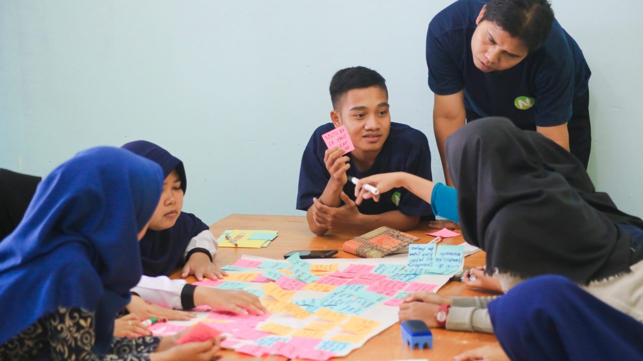 A roundtable discussion of people writing on sticky notes