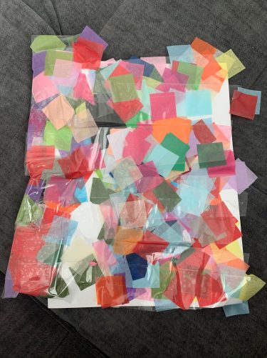 A piece of paper covered in squares of multicolored tissue paper