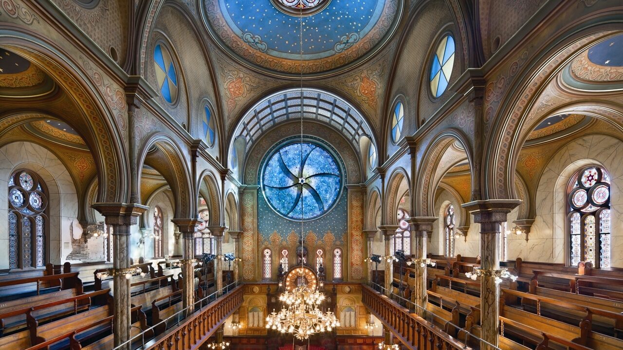 Interior view of a historic synagogue with round stained-glass windows