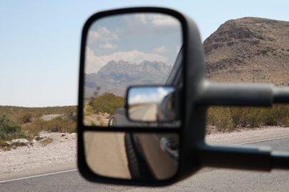 A rearview mirror of a vehicle in the desert