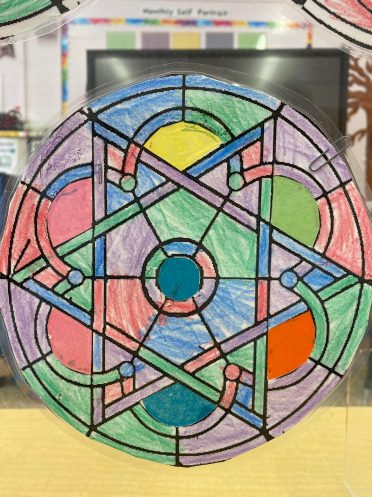 A laminated coloring page in the shape of one of the circular stained glass windows