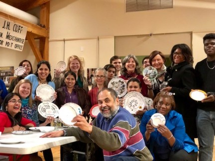 A group of people holding up pottery with unique designs on it