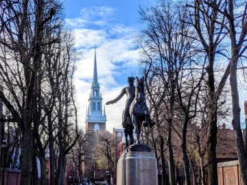 A public square with a state of Paul Revere and the steeple of a church visible in the background.