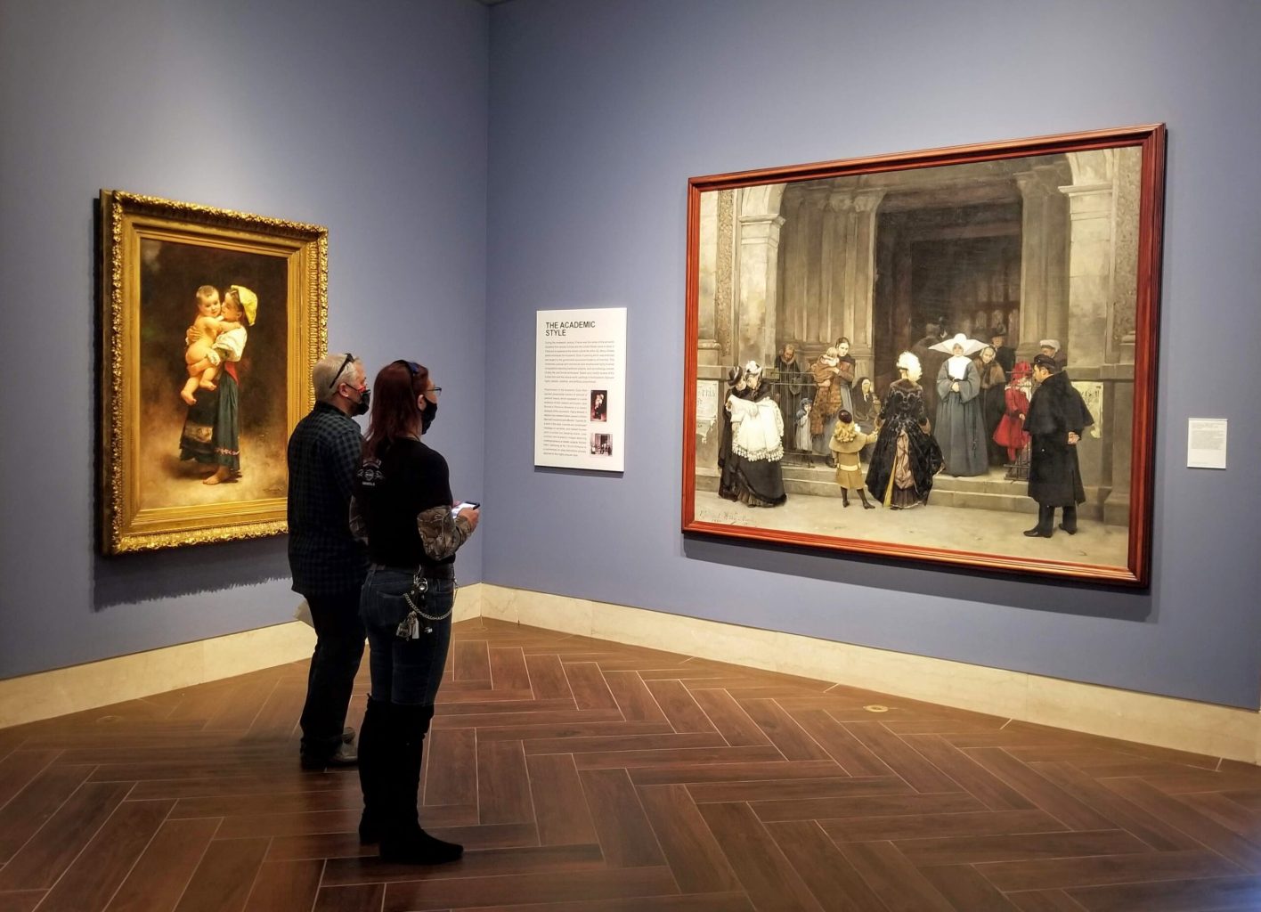 Visitors in front of a painting of a group of people outside the entrance of a church