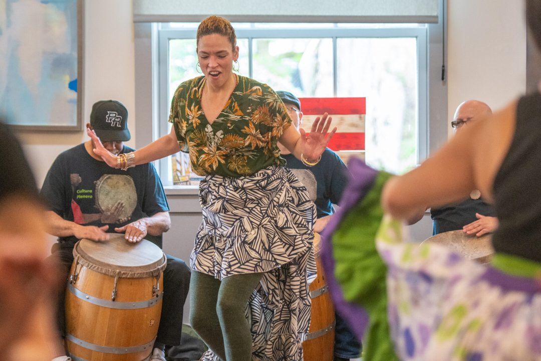 A dancer mid-pose in the center of a drum circle