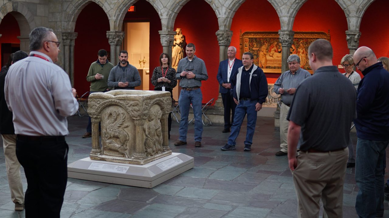 A group of people standing around a relief sculpture on a pedestal in a museum gallery