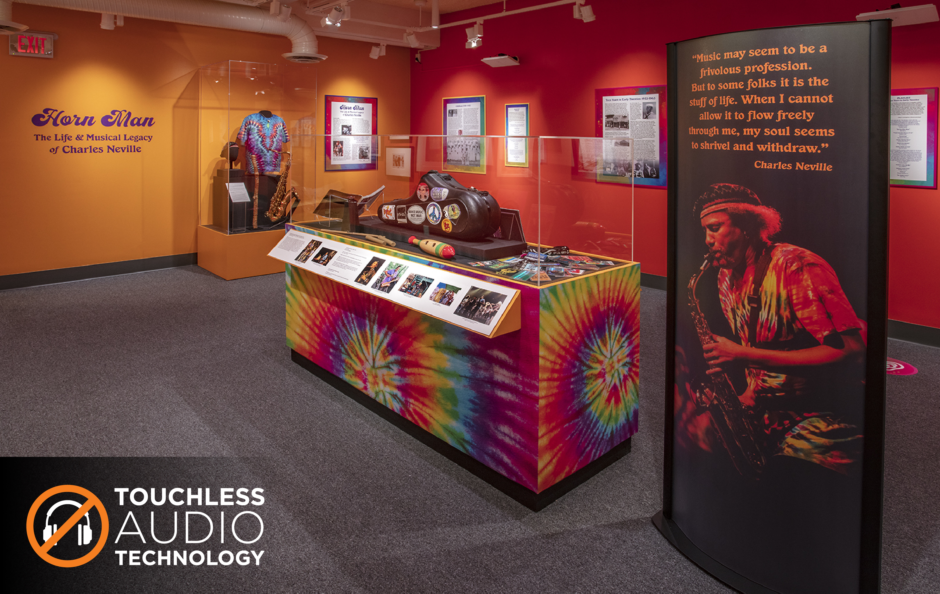 A display of music ephemera in a museum gallery, with a sign showing a picture of the musician Charles Neville and the quote "Museum may seem to be a frivolous profession. But to some folks it is the stuff of life. When I cannot allow it to flow freely through me, my soul seems to shrivel and withdraw."