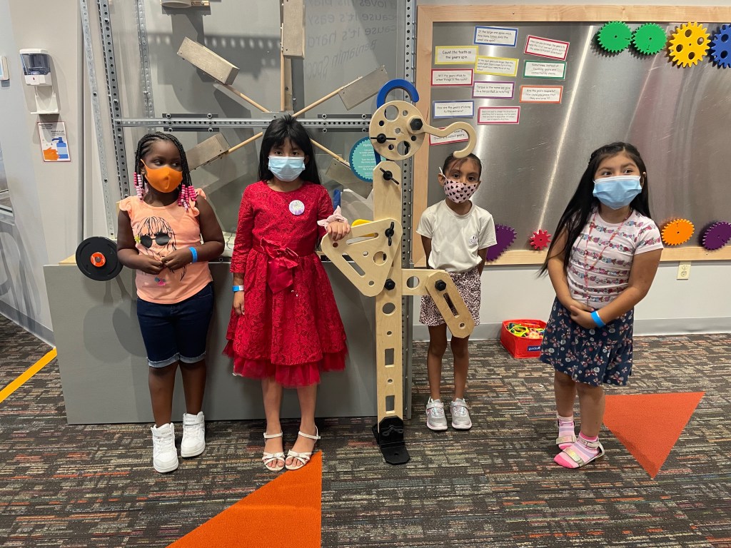 A group portrait of children in a children's museum space wearing masks