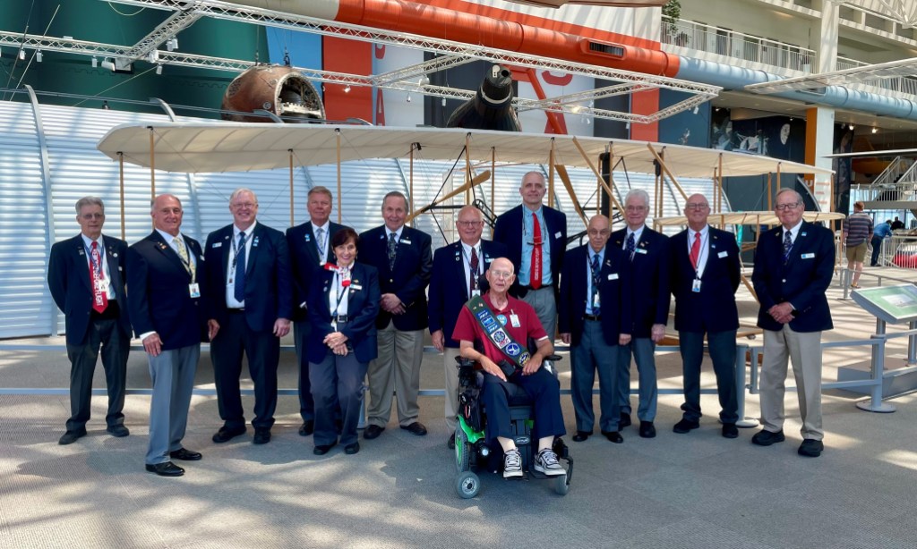 A group portrait of volunteers in docent uniforms in front of an aircraft