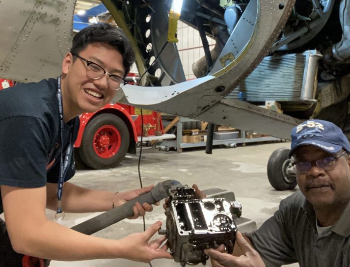 Two volunteers working with an engine part