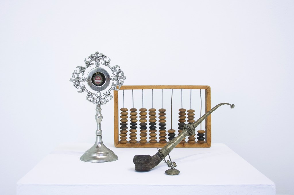 Silver and wood objects, including an abacus, displayed on a pedestal