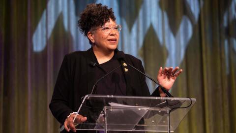 Sandra Jackson-Dumont standing at a podium and gesturing with her hands