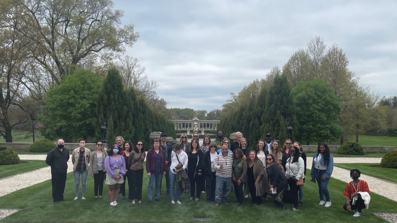 A group portrait of people standing on the lawn of a large house