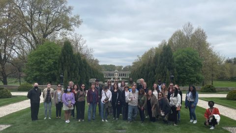 A group portrait of people standing on the lawn of a large house