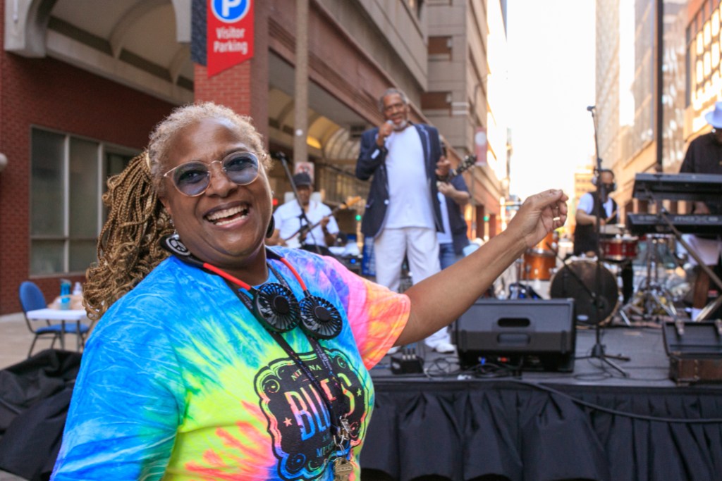 A person dancing in front of a band performing on an outdoor stage