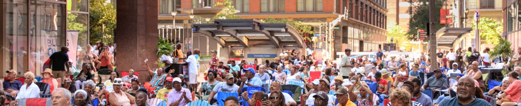 A crowd of people sitting in stadium chairs on a city street