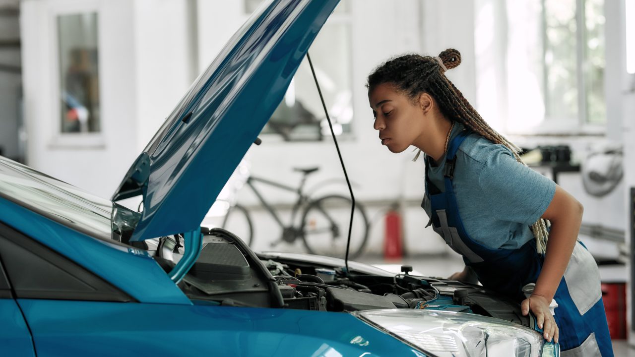A mechanic inspecting under the hood of a car