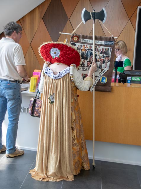 A guest in a queen costume checking out at a registration desk