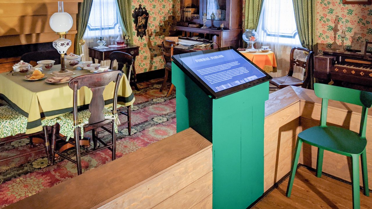 A historic house interior with a touchscreen panel in front of a display