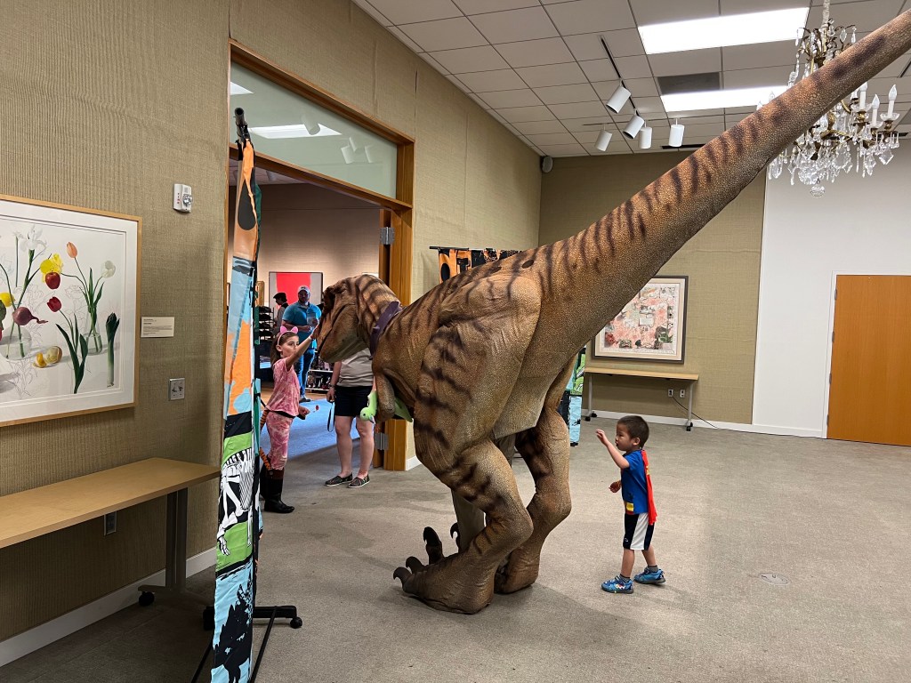 Children standing near a large dinosaur puppet