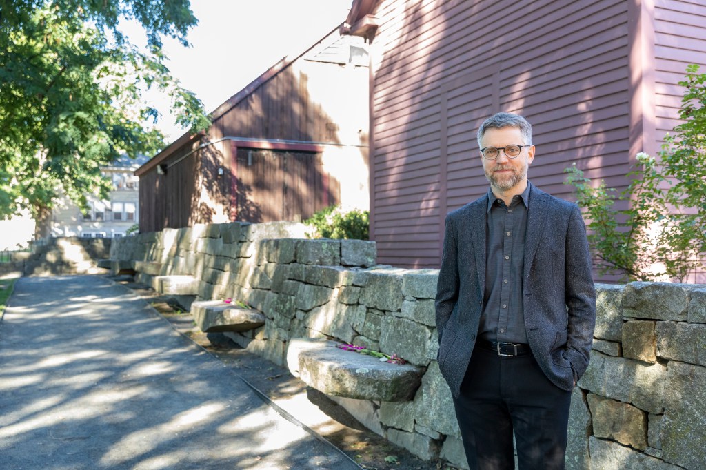 A person standing outside of a historic building with a stone fence