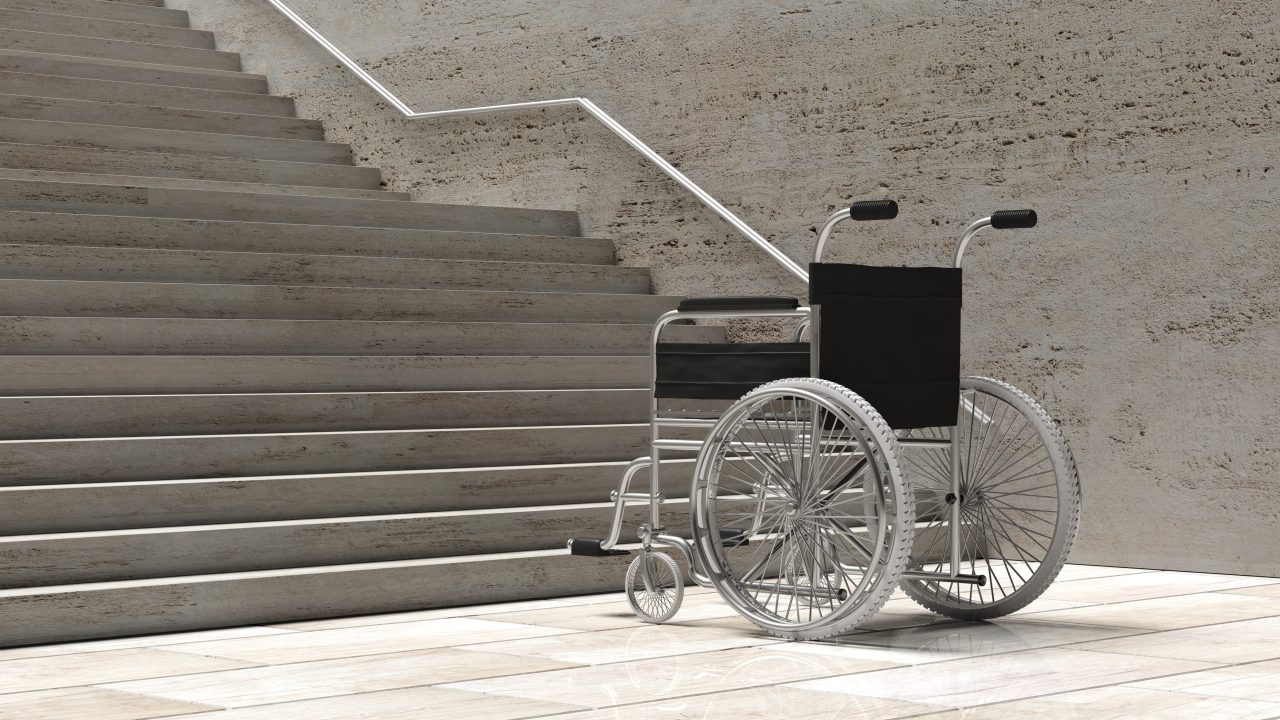A wheelchair parked at the bottom of a concrete staircase
