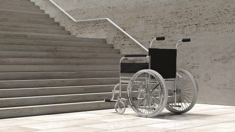 A wheelchair parked at the bottom of a concrete staircase