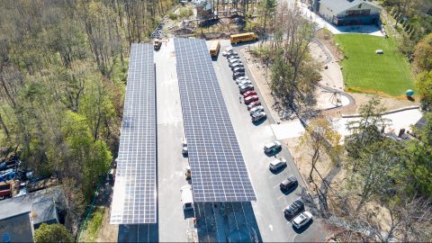 An aerial view of a parking lot with large solar panels staked into the ground