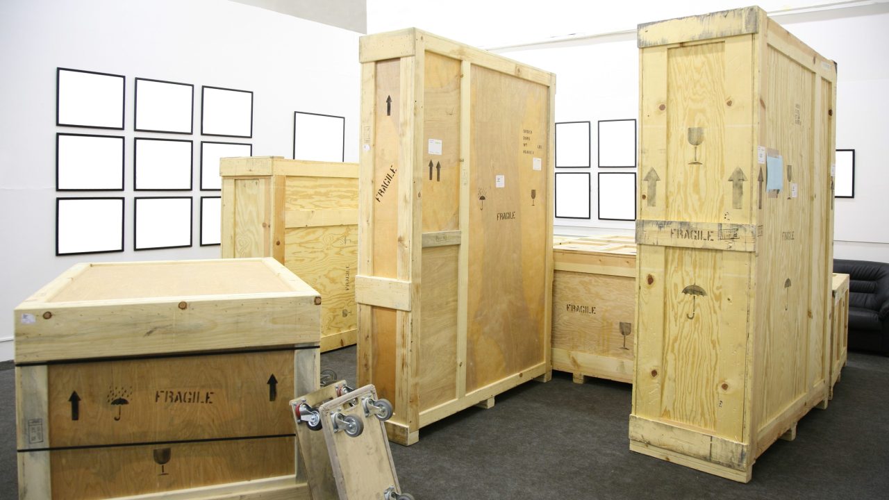 A set of crates in a gallery with blank frames on the walls