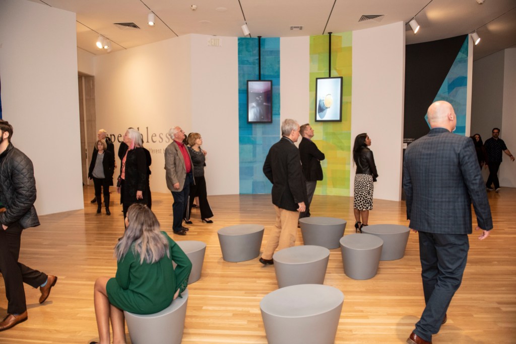 A gallery space with stools positioned on the floor in the middle