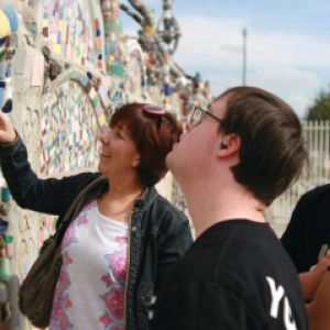 Three people look at a colorful mosaic wall.