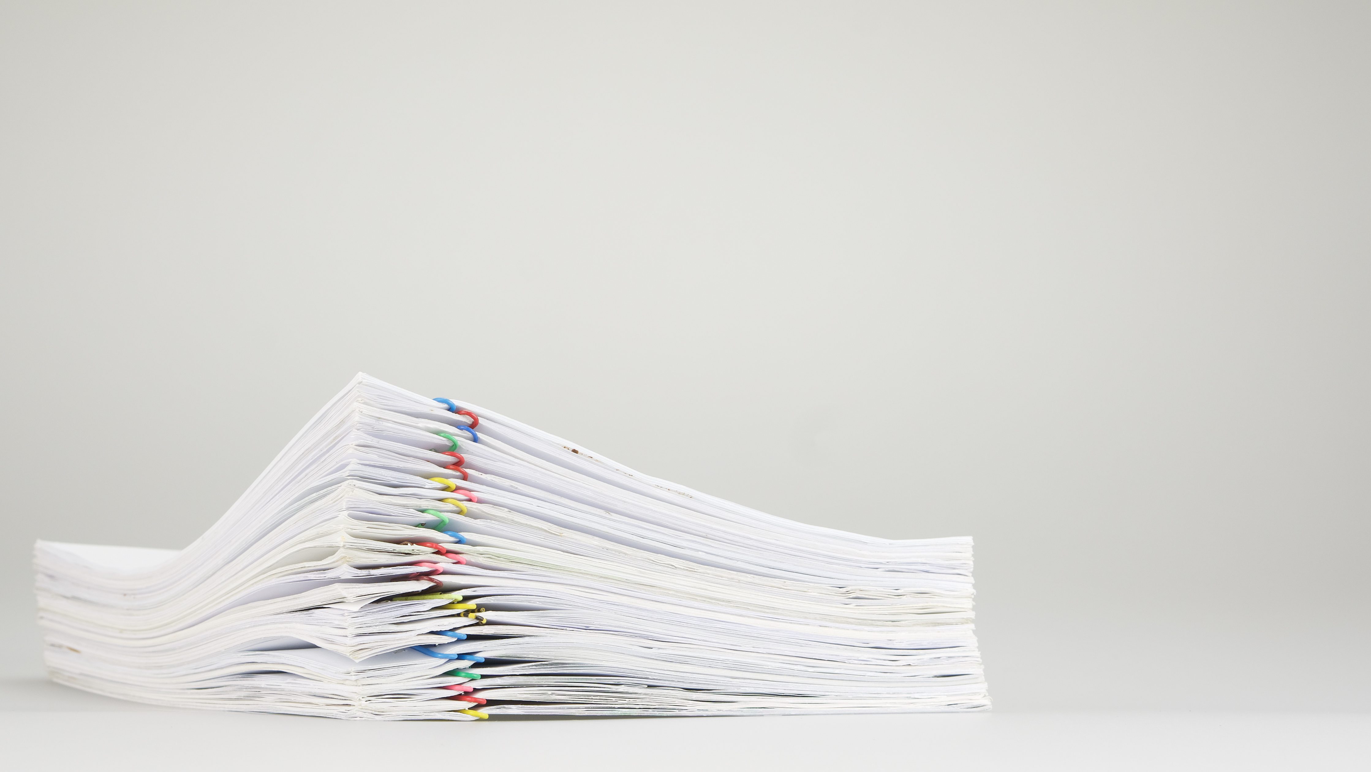 Pile overload of paper with colorful paper clip place on white background.