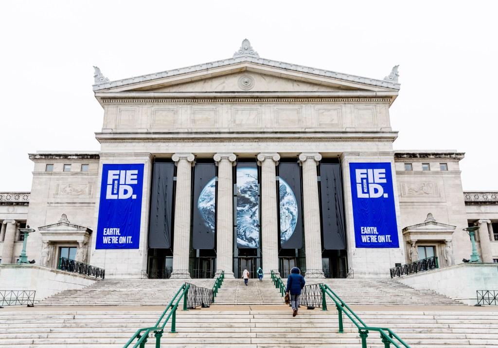 The entrance to the Field Museum, with a series of banners in between the columns displaying a picture of the Earth and the slogan "Earth. We're on it."