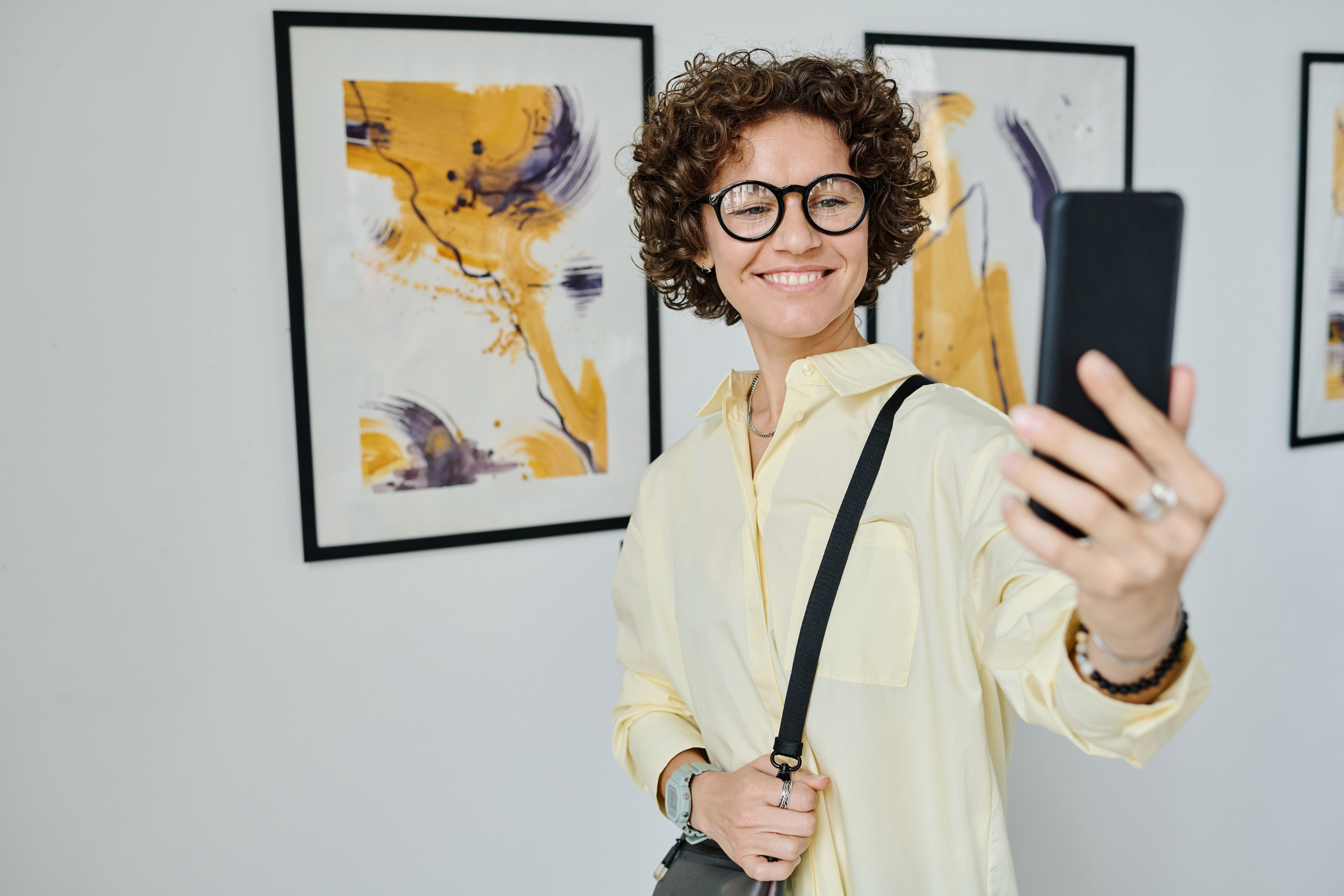 a photograph of a person taking a selfie in front of an art exhibit
