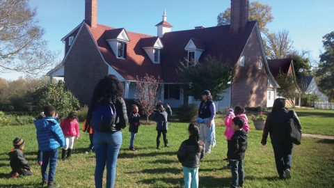 A group stands outside a white historic house.