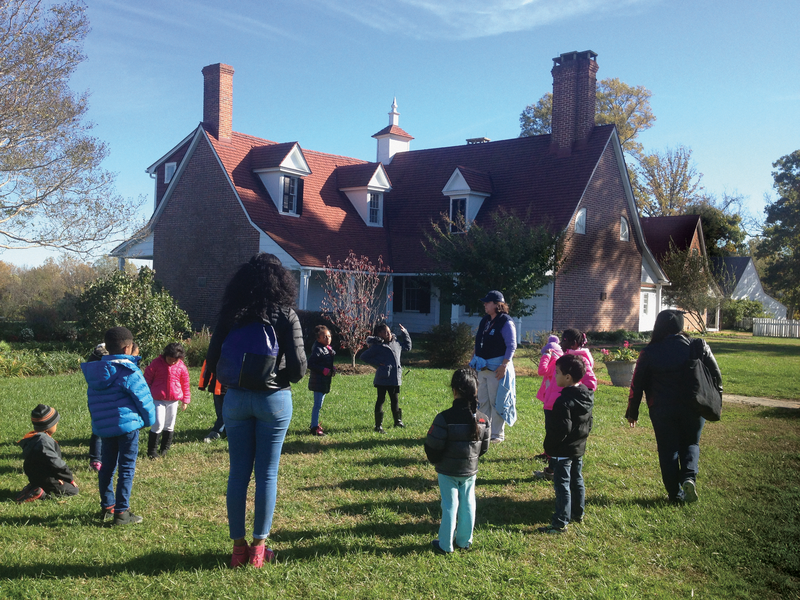 A group stands outside a white historic house.