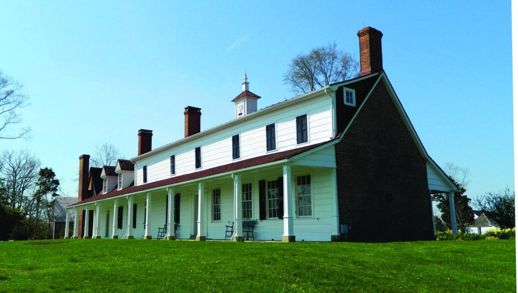 An exterior view of the Sotterley mansion, a white colonial farmhouse.